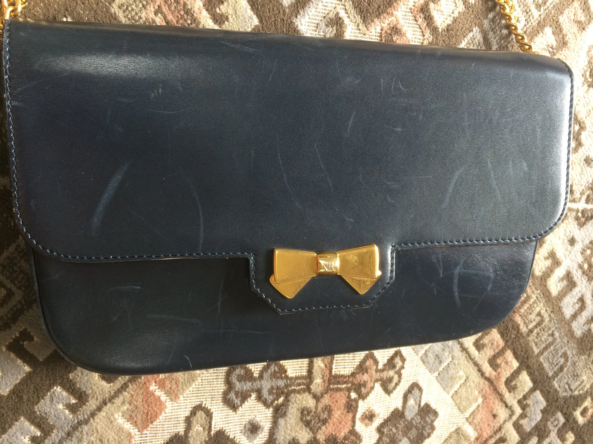 Vintage Nina Ricci navy leather clutch chain shoulder bag, classic purse with golden ribbon logo motif. Mod and chic daily purse.