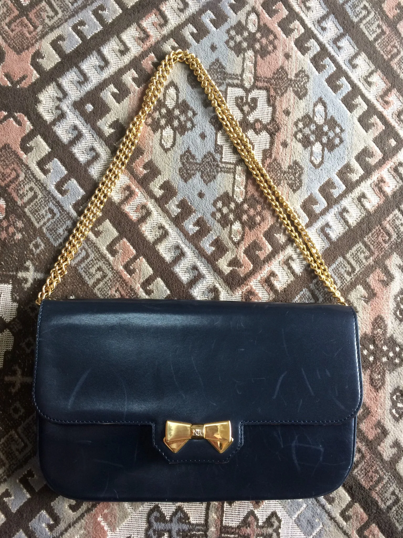 Vintage Nina Ricci navy leather clutch chain shoulder bag, classic purse with golden ribbon logo motif. Mod and chic daily purse.